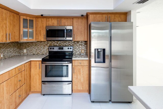 17359 NW 66th Ct, Hialeah, FL 33015 - kitchen with stainless steel appliances, glass insert cabinets, light countertops, brown cabinets, and tasteful backsplash