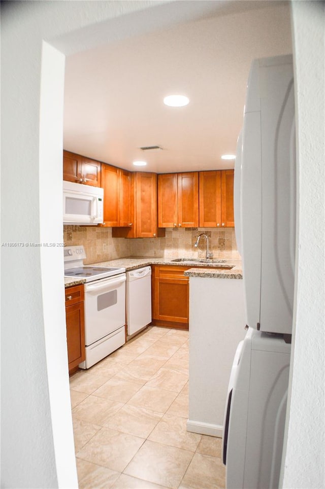 733 SE 1st Way Unit 206, Deerfield Beach, FL 33441 - kitchen with white appliances, tasteful backsplash, stacked washer and clothes dryer, brown cabinets, and recessed lighting