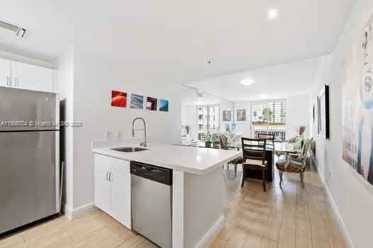185 SE 14th Ter Unit 1410, Miami, FL 33131 - kitchen featuring stainless steel appliances, a sink, light countertops, light wood-style floors, and white cabinets