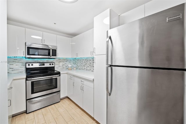185 SE 14th Ter Unit 1410, Miami, FL 33131 - kitchen with stainless steel appliances, light countertops, backsplash, white cabinets, and light wood-style floors
