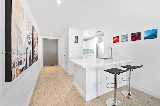 185 SE 14th Ter Unit 1410, Miami, FL 33131 - kitchen with freestanding refrigerator, a sink, white cabinetry, light wood-style flooring, and light countertops