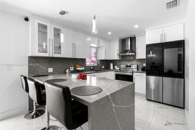 3201 NE 9th Ter, Pompano Beach, FL 33064 - kitchen with wall chimney range hood, stainless steel appliances, a peninsula, light marble finish floors, and recessed lighting