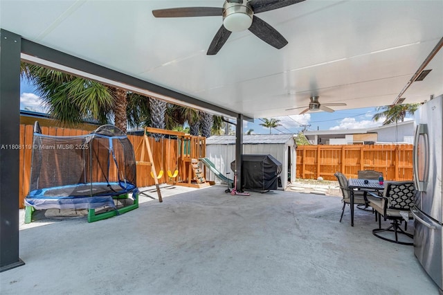 3201 NE 9th Ter, Pompano Beach, FL 33064 - fenced backyard featuring a trampoline, a patio, outdoor dining area, ceiling fan, and a playground