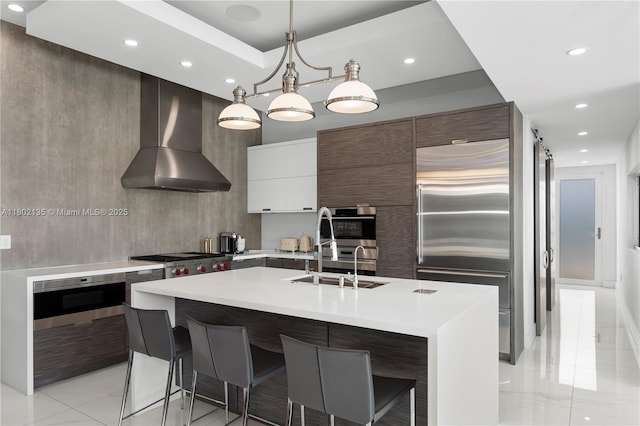 12880 N Bayshore Dr, North Miami, FL 33181 - kitchen featuring built in appliances, modern cabinets, wall chimney range hood, light countertops, and recessed lighting