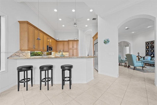 11034 Via, San Remo, Boynton Beach, FL 33437 - kitchen featuring arched walkways, ornamental molding, stainless steel appliances, ceiling fan, and backsplash