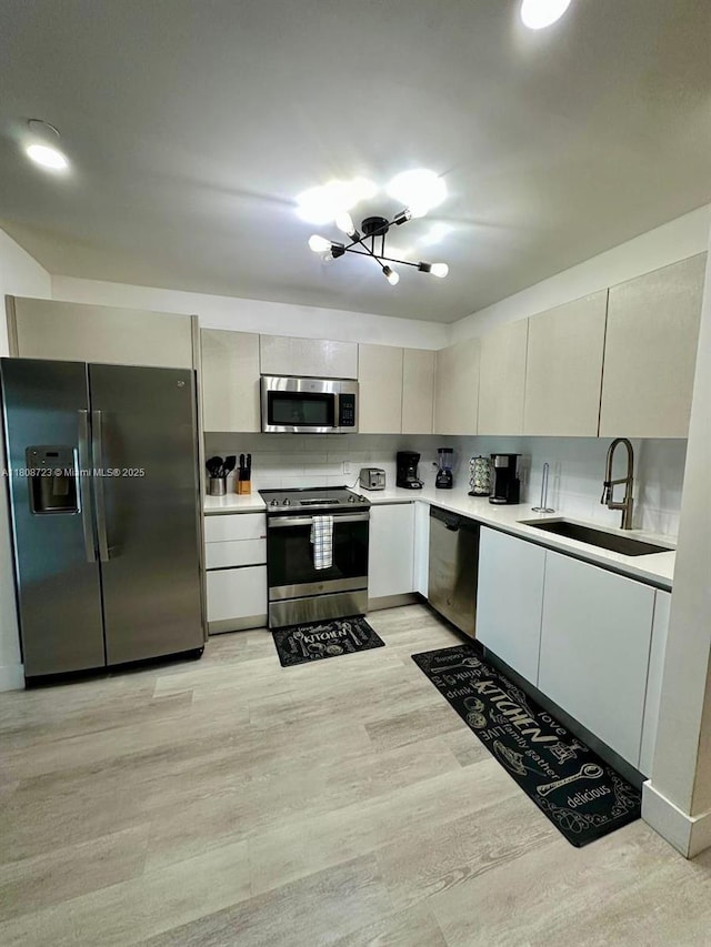 19380 NE 26th Ave Unit 305, Miami, FL 33180 - kitchen featuring stainless steel appliances, a sink, light countertops, modern cabinets, and light wood-type flooring