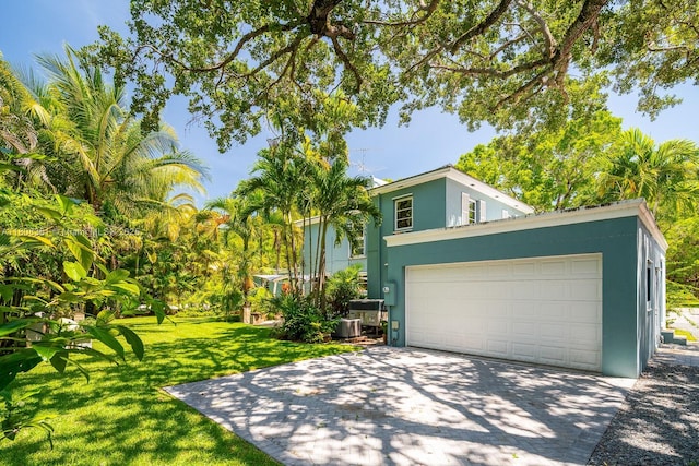 3245 Riviera Dr, Coral Gables, FL 33134 - view of front of property featuring stucco siding, driveway, a garage, a front yard, and central AC