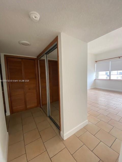 18061 Biscayne Blvd Unit Ph02, Aventura, FL 33160 - hall featuring light tile patterned floors, baseboards, and a textured ceiling