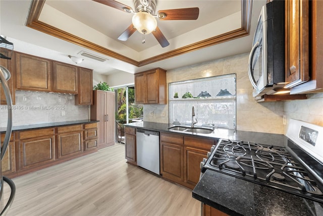 9362 NW 24th Pl, Sunrise, FL 33322 - kitchen featuring stainless steel appliances, a sink, a tray ceiling, backsplash, and brown cabinetry