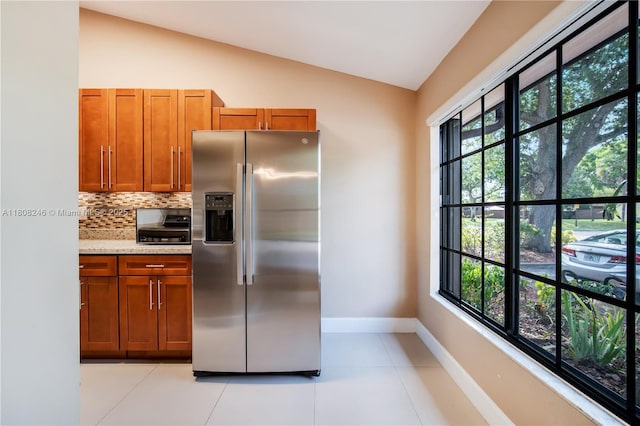 10760 Hickory Ave, Pembroke Pines, FL 33026 - kitchen with stainless steel refrigerator with ice dispenser, brown cabinetry, baseboards, vaulted ceiling, and backsplash
