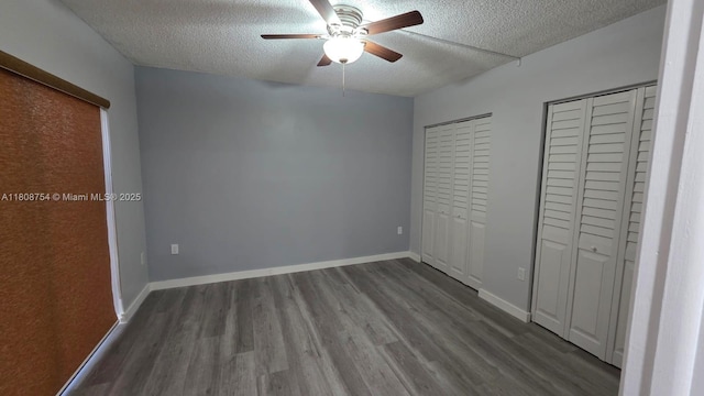 11890 SW 18th Ter Unit 112, Miami, FL 33175 - unfurnished bedroom featuring a textured ceiling, two closets, dark wood-style floors, and ceiling fan