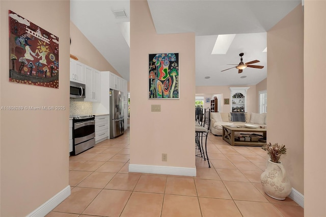 2215 SW 14th Pl, Boca Raton, FL 33486 - kitchen with stainless steel appliances, a skylight, white cabinets, a ceiling fan, and lofted ceiling
