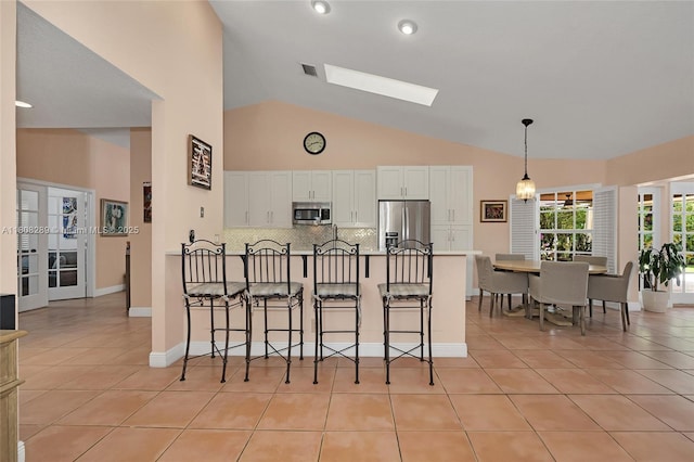 2215 SW 14th Pl, Boca Raton, FL 33486 - kitchen with stainless steel appliances, light tile patterned floors, white cabinetry, tasteful backsplash, and a peninsula
