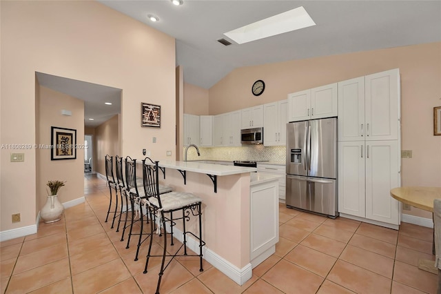 2215 SW 14th Pl, Boca Raton, FL 33486 - kitchen with appliances with stainless steel finishes, light tile patterned flooring, a breakfast bar area, a peninsula, and high vaulted ceiling