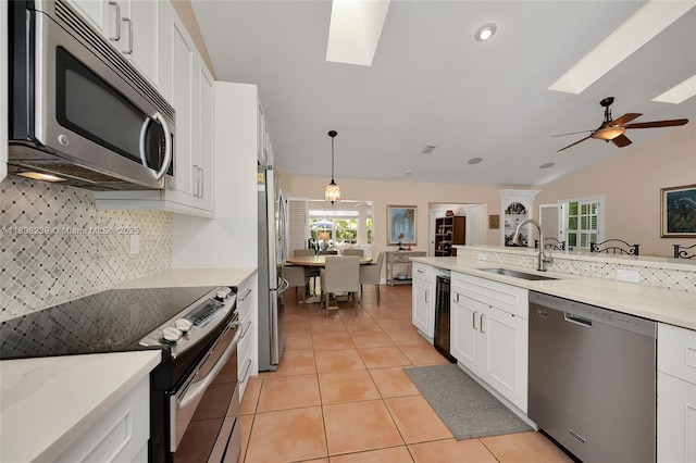 2215 SW 14th Pl, Boca Raton, FL 33486 - kitchen featuring stainless steel appliances, a skylight, tasteful backsplash, white cabinetry, and lofted ceiling