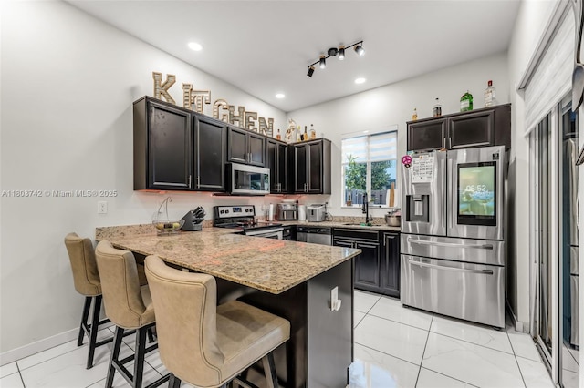 17612 SW 153rd Ave, Miami, FL 33187 - kitchen with appliances with stainless steel finishes, a sink, a peninsula, a kitchen bar, and light stone counters