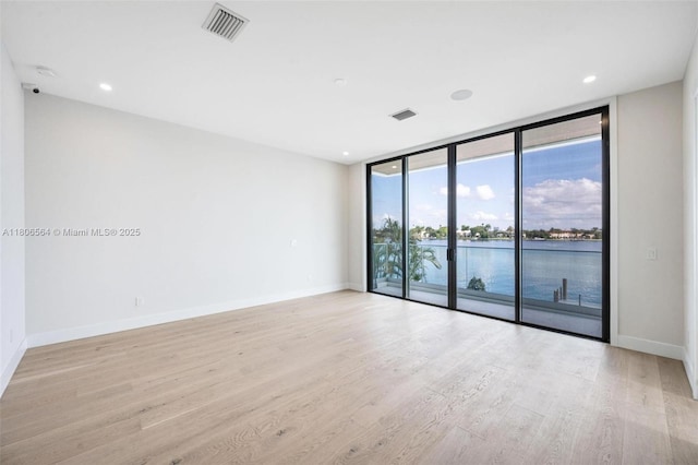 1351 Stillwater Dr, Miami Beach, FL 33141 - empty room with expansive windows, light wood-style floors, a water view, and baseboards