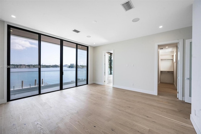 1351 Stillwater Dr, Miami Beach, FL 33141 - empty room with light wood finished floors, expansive windows, and a water view