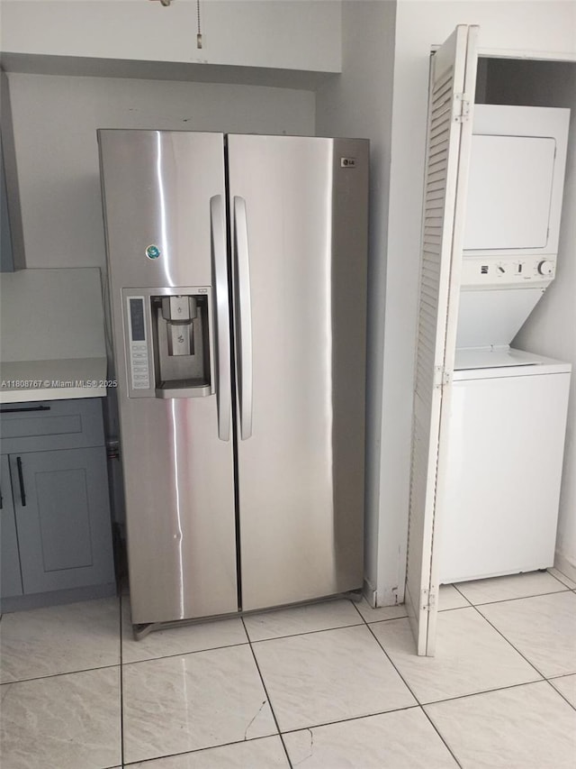 1800 SW 25th St Unit 2305, Miami, FL 33133 - kitchen featuring stainless steel refrigerator with ice dispenser, stacked washer and clothes dryer, light countertops, light tile patterned floors, and gray cabinets