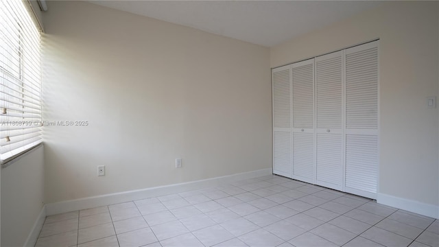 9300 W Flagler St Unit 112D, Miami, FL 33174 - unfurnished bedroom featuring light tile patterned flooring, a closet, and baseboards