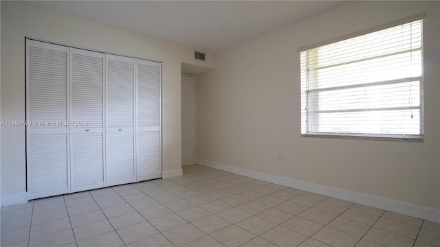 9300 W Flagler St Unit 112D, Miami, FL 33174 - unfurnished bedroom featuring multiple windows, a closet, baseboards, and light tile patterned flooring