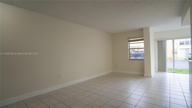 9300 W Flagler St Unit 112D, Miami, FL 33174 - spare room with a textured ceiling, light tile patterned flooring, and baseboards