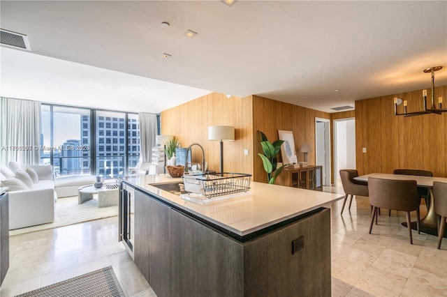 68 SE 6th St Unit 1403, Miami, FL 33131 - kitchen featuring wood walls, a kitchen island with sink, a chandelier, open floor plan, and light countertops
