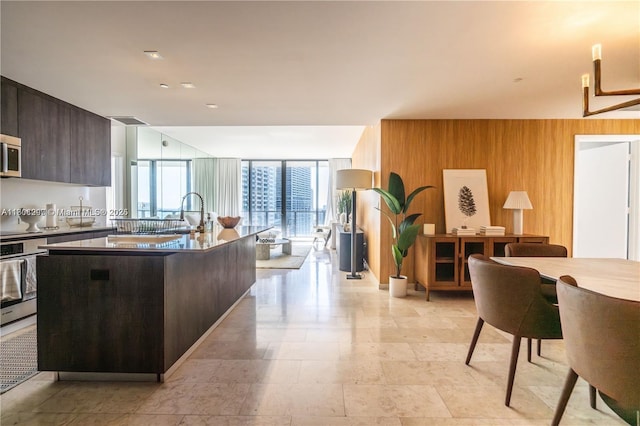 68 SE 6th St Unit 1403, Miami, FL 33131 - kitchen featuring appliances with stainless steel finishes, wood walls, modern cabinets, floor to ceiling windows, and a center island with sink