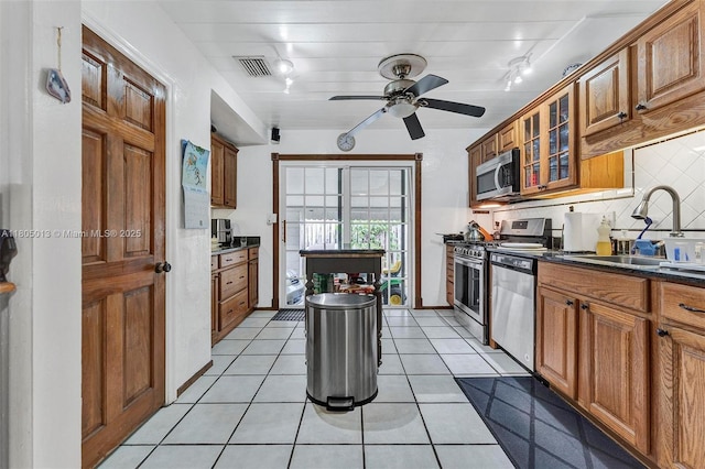 2442 Fillmore St, Hollywood, FL 33020 - kitchen featuring appliances with stainless steel finishes, dark countertops, rail lighting, and brown cabinetry