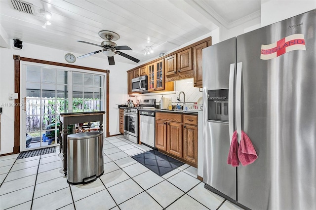 2442 Fillmore St, Hollywood, FL 33020 - kitchen with appliances with stainless steel finishes, brown cabinetry, decorative backsplash, ceiling fan, and glass insert cabinets