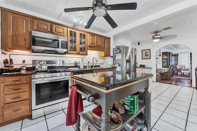 2442 Fillmore St, Hollywood, FL 33020 - kitchen with appliances with stainless steel finishes, a ceiling fan, arched walkways, brown cabinets, and light tile patterned flooring