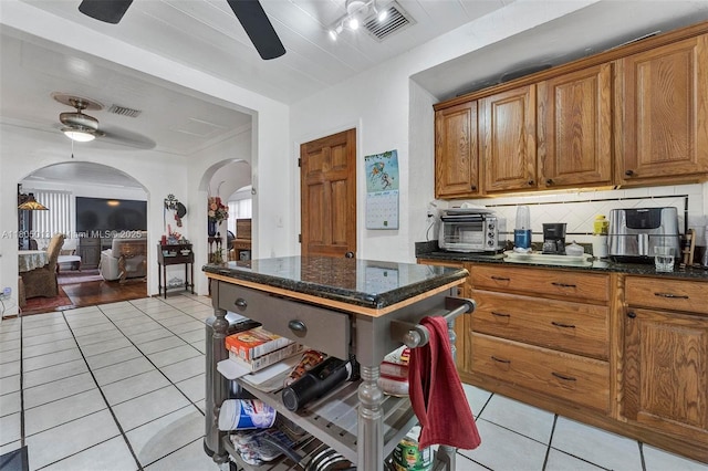 2442 Fillmore St, Hollywood, FL 33020 - kitchen featuring ceiling fan, arched walkways, light tile patterned floors, and brown cabinets