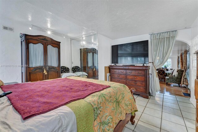 2442 Fillmore St, Hollywood, FL 33020 - bedroom featuring tile patterned floors, arched walkways, rail lighting, and a textured ceiling