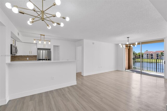 2173 Renaissance Blvd Unit 204, Miramar, FL 33025 - unfurnished living room with a chandelier, light wood finished floors, a textured ceiling, and a water view