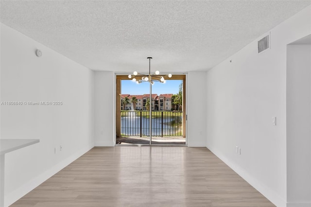 2173 Renaissance Blvd Unit 204, Miramar, FL 33025 - unfurnished room with a chandelier, a textured ceiling, wood finished floors, and a water view