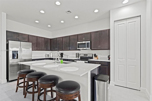 16450 Sea Turtle Pl, Loxahatchee, FL 33470 - kitchen with stainless steel appliances, light tile patterned floors, a sink, a breakfast bar area, and light countertops