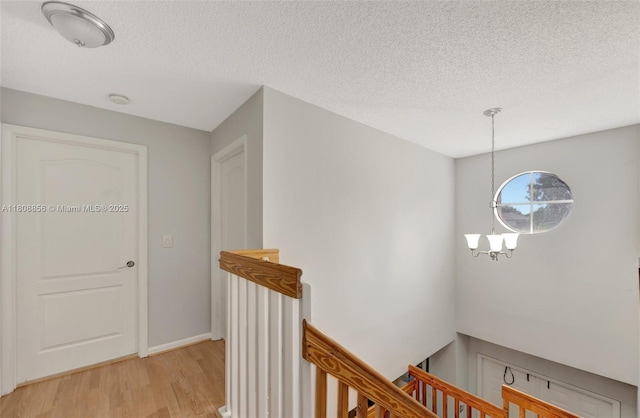 21519 SW 90th Ave, Cutler Bay, FL 33189 - corridor featuring an upstairs landing, light wood-style floors, a textured ceiling, a chandelier, and baseboards