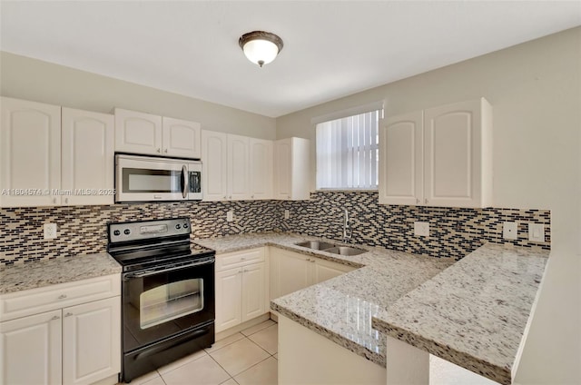 8199 W 36th Ave Unit 5, Hialeah, FL 33018 - kitchen with stainless steel microwave, black electric range, a peninsula, light stone countertops, and tasteful backsplash
