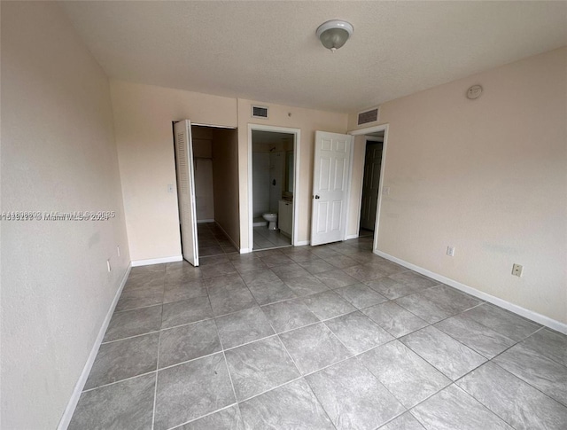 15480 SW 284th St Unit 2304, Homestead, FL 33033 - unfurnished bedroom featuring baseboards, a closet, tile patterned floors, ensuite bath, and a textured ceiling