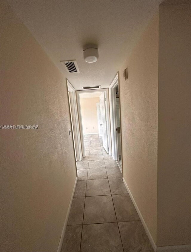15480 SW 284th St Unit 2304, Homestead, FL 33033 - corridor with a textured wall, baseboards, and tile patterned flooring