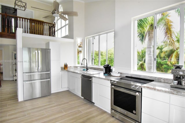 168 Indian Mound Trl, Tavernier, FL 33070 - kitchen with appliances with stainless steel finishes, light stone counters, plenty of natural light, white cabinets, and a towering ceiling