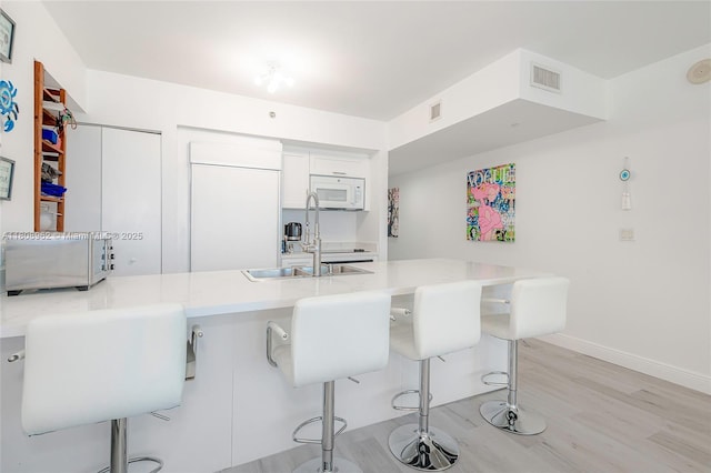 1830 S Ocean Dr Unit 1605, Hallandale Beach, FL 33009 - kitchen featuring paneled fridge, white microwave, a breakfast bar, light wood-style floors, and light countertops