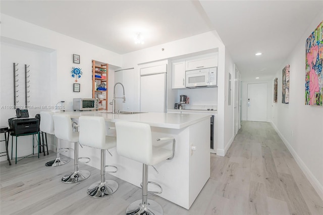 1830 S Ocean Dr Unit 1605, Hallandale Beach, FL 33009 - kitchen featuring white microwave, a sink, light wood-style floors, a breakfast bar area, and recessed lighting