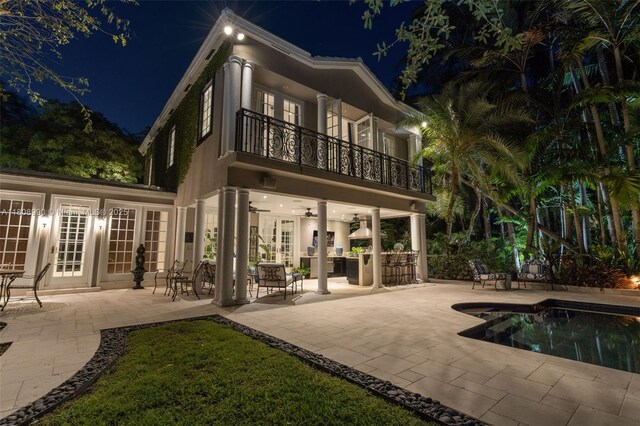 7360 SW 164th St, Palmetto Bay, FL 33157 - back of house at twilight featuring french doors, a balcony, a patio area, ceiling fan, and an outdoor pool