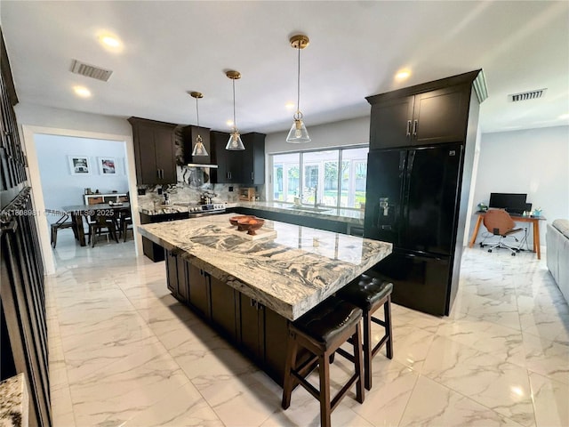 14870 SW 152nd Ct, Miami, FL 33196 - kitchen featuring freestanding refrigerator, light marble finish floors, a breakfast bar area, tasteful backsplash, and recessed lighting