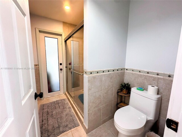 14870 SW 152nd Ct, Miami, FL 33196 - bathroom featuring tile patterned floors, a stall shower, tile walls, toilet, and a wainscoted wall