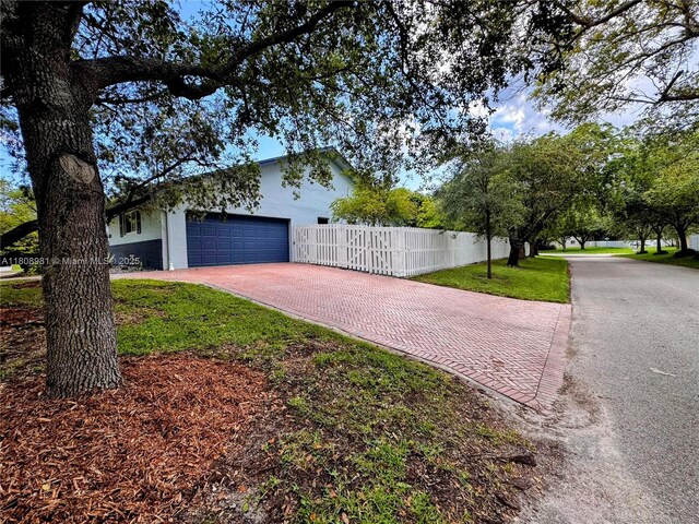 14870 SW 152nd Ct, Miami, FL 33196 - view of side of home featuring decorative driveway, a garage, and stucco siding