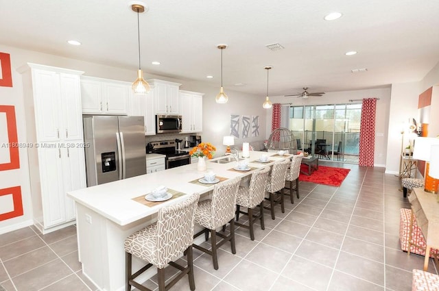 1515 Carey Palm Cir, Kissimmee, FL 34747 - kitchen featuring stainless steel appliances, light tile patterned floors, a sink, a ceiling fan, and a kitchen bar