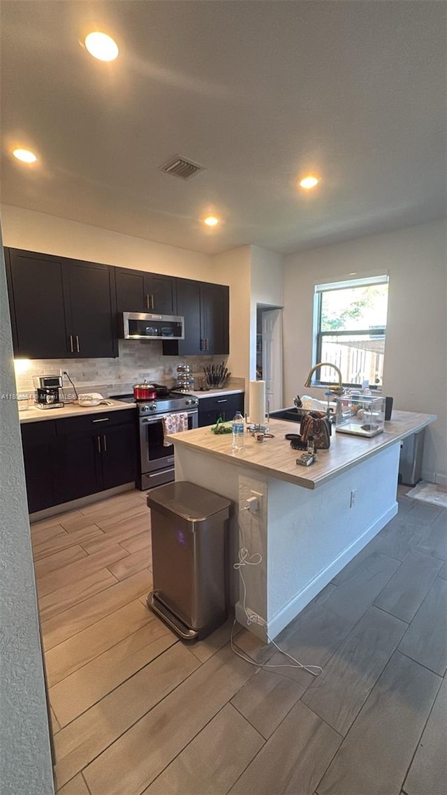 13416 SW 287th St Unit A, Homestead, FL 33033 - kitchen with stainless steel range with gas stovetop, extractor fan, wood tiled floors, dark cabinets, and light countertops