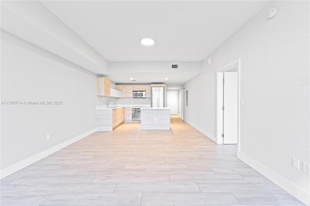 16385 Biscayne Blvd Unit 404, North Miami Beach, FL 33160 - kitchen with stainless steel microwave, light brown cabinets, light countertops, baseboards, and light wood finished floors